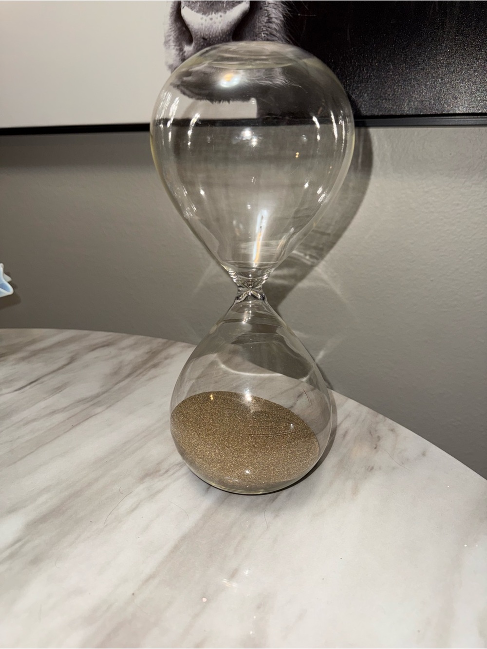 clear glass hourglass sand timer filled with light-colored or brownish sand